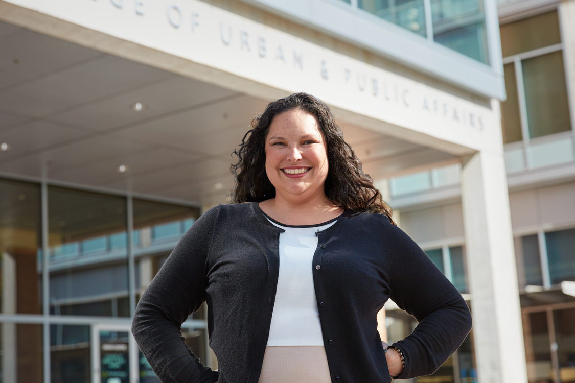 Dr. Zapata stands smiling in PSU's urban center with her hands on her hips.